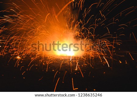 View of explosive yellow and orange ground firework during celebration of the Yee Peng Lantern Festival in Chiang Mai, Thailand. Beautiful explosive firework in the dark background. 