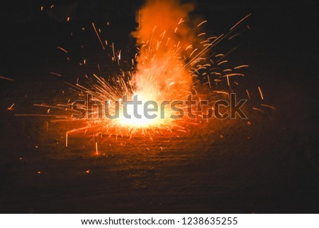 View of explosive yellow and orange ground firework during celebration of the Yee Peng Lantern Festival in Chiang Mai, Thailand. Beautiful explosive firework in the dark background. 