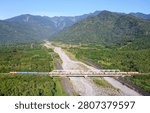View of an express train dashing through an iron bridge over the dried riverbed of Kanon River on a sunny day with beautiful mountains under blue clear sky in background in Guangfu Township, Hualien County, Taiwan.
This magnificent wide-angle aerial photograph captures the breathtaking natural splendor and rhythmic infrastructure of eastern Taiwan