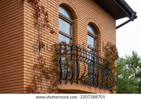 view of the facade of the building in the city, red brick house balcony with long windows, autumn decoration of the wall, modern architecture
