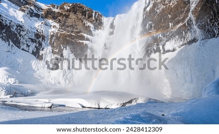 View of the famous Skógafoss ( Skogafoss) waterfall during winter in the south of Iceland near Skogar town. Amazing cascade with ice and snow and partially frozen river.