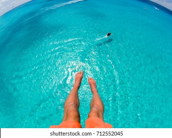 View of feet parasailing with the speed boat in the sea background.