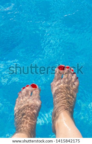 View of female feet submerged under water. Nails are painted red