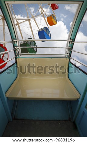 View of a ferris wheel from inside a carousel cab high above ground.