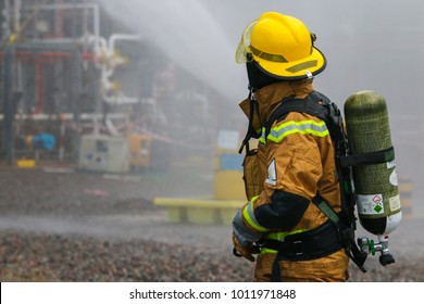 View Of A Fire Fighter With Compressed Air Tank. Visible Water Mist In The Background.