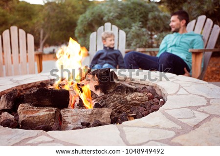 view of firepit and happy smiling family of two, father and son, enjoying time together in the background