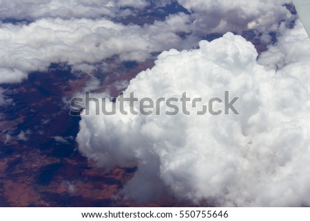 View of  fluffy white cumulus clouds shadowing a barren desert below , flying to  Broome, North Western Australia by aeroplane on a hot afternoon in the summer Wet Season is beautifully exhilarating.