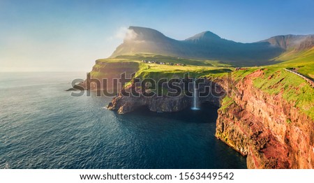 View from flying drone. Majestic morning scene of Mulafossur Waterfall. Stunning summer view of Vagar island, Faroe Islands,  Denmark, Europe. Beauty of nature concept background.