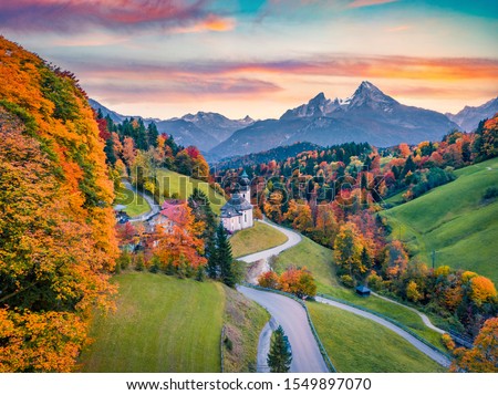 View from flying drone Maria Gern church with Hochkalter peak on background. Fantastic autumn sunrise in of Bavaria Alps. Fantastic evening landscape of Germany countryside. 