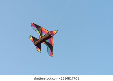 View to the flying kite in the blue sky. The kite has shape of bird or airplane and colourful body. Great experience for kids and adults.  - Powered by Shutterstock