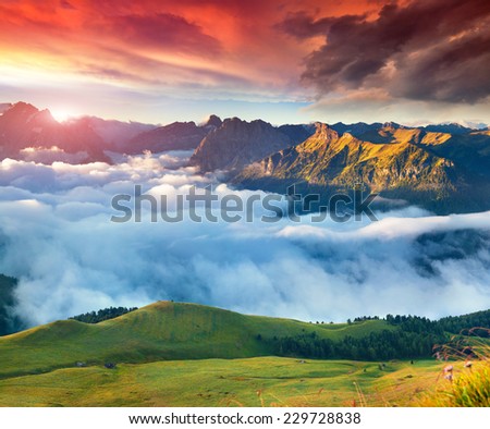 View of the foggy Val di Fassa valley with passo Sella. National Park. Dolomites, South Tyrol. Location Canazei, Campitello, Mazzin. Italy, Europe. Dramatic sky.
