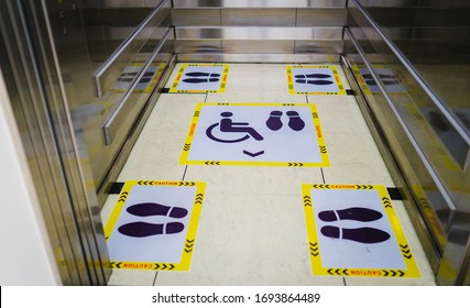 View of footprint sign for stand in lift. Social distancing with COVID-19 coronavirus crisis.yellow footprint sign with text caution social distance, Social distancing the elevator (Lift) in hospital.