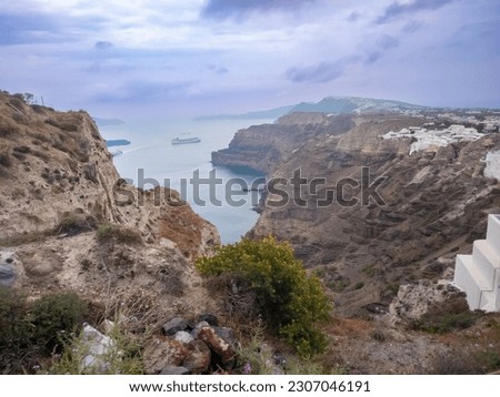View form above of the high cliff of a mountain by the sea in a blur background of sea, boats, buildings on the cliff, and mountain from afar