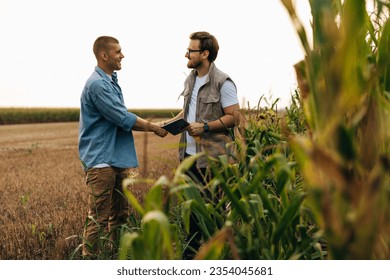 View form the corn field of two men shaking hands.