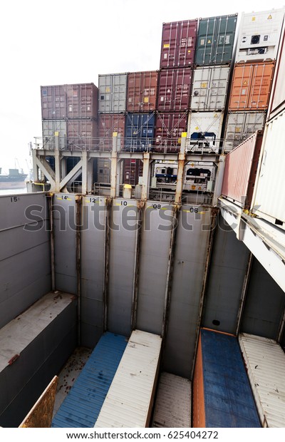 View of\
a freighter ship\'s storage compartment, half full with containers,\
in the middle of the loading\
process.