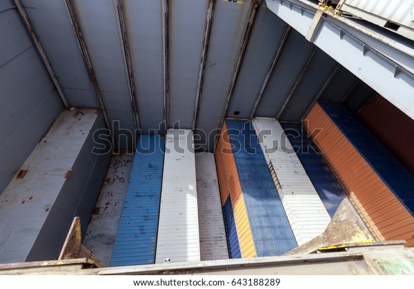 View of\
a freighter ship\'s storage compartment, half full with containers,\
in the middle of the loading\
process.