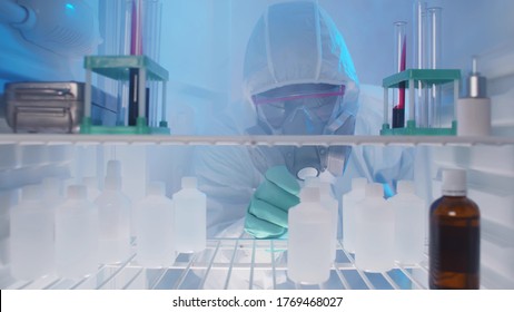 View from fridge of lab technician in protective overall and mask taking bottle with chemicals from refrigerator. Doctor taking medicine from fridge in hospital - Powered by Shutterstock