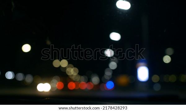 View\
from the front window of the car on the night road with blurry\
lights of passing cars and lighting lamps. Out-of-focus view of an\
unrecognizable road at night with beautiful\
bokeh.