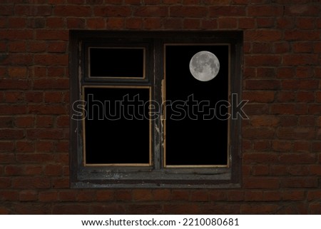 view of the full moon in an old window located in a brick wall