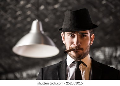 View of a gangster man is smoking a cuban cigar.