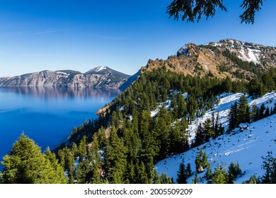 View of Garfield Peak, a popular destination hike inside of Crater Lake National Park, seen with blue skies and sunny conditions with a bit of snow left late into spring