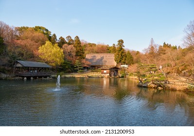 The View Of The Gassho Style House And Watermill On The Okuike Pond In Higashiyama Zoo And Botanical Garden In The Evening Light. Nagoya. Japan