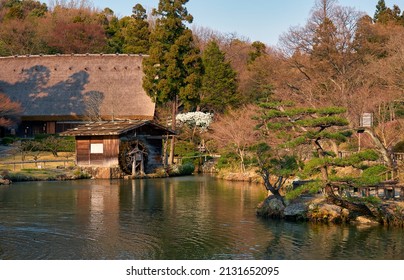 The View Of The Gassho Style House And Watermill On The Okuike Pond In Higashiyama Zoo And Botanical Garden In The Evening Light. Nagoya. Japan