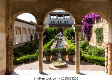 View of The Generalife courtyard, with its famous fountain and garden through an arch. Alhambra de Granada complex at Granada, Spain, Europe on a bright summer day