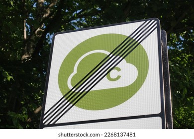 View of a generic clean air zone congestion charge road sign seen at the end of the zone with leafy green trees in the background