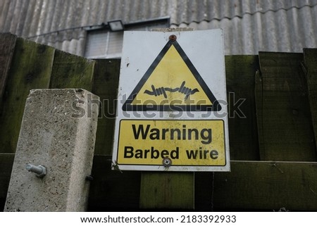 View of a generic sign reading 'warning barbed wire'