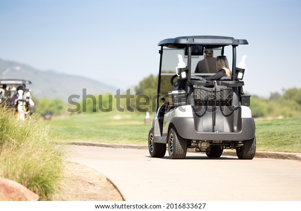 A view of a golf cart on the trail to the next golf\
course hole.