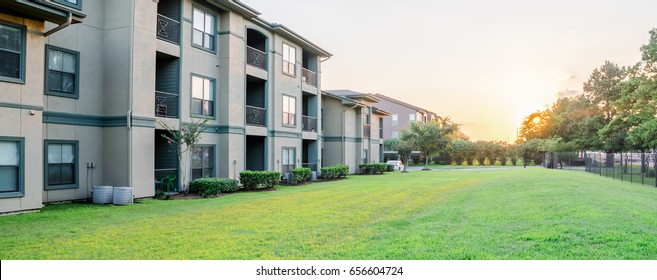 View from grassy backyard of a typical apartment complex building in suburban area at Humble, Texas, US. Sunset with warm light. Panorama style.