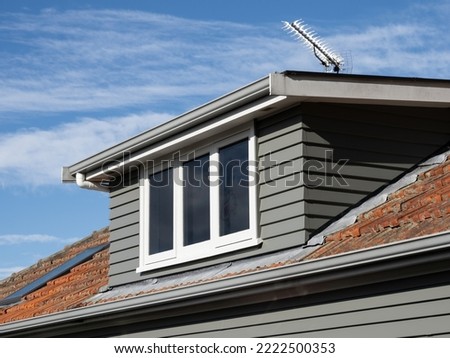 View of gray shed roof dormer loft with white window and clay colored tiles ストックフォト © 