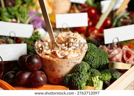 A view of a grazing board, featuring a cup of pimento cheese.