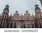 View of the Great Armoury building in Gdansk. The building is richly decorated. There building has many spikey towers. Renaissance building