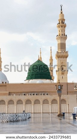view of the green dome of the Nabawi Mosque from afar, with slightly overcast clouds in the background