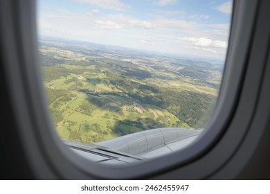 View of Green Fields From Airplane Window During Daytime Flight Over Countryside
