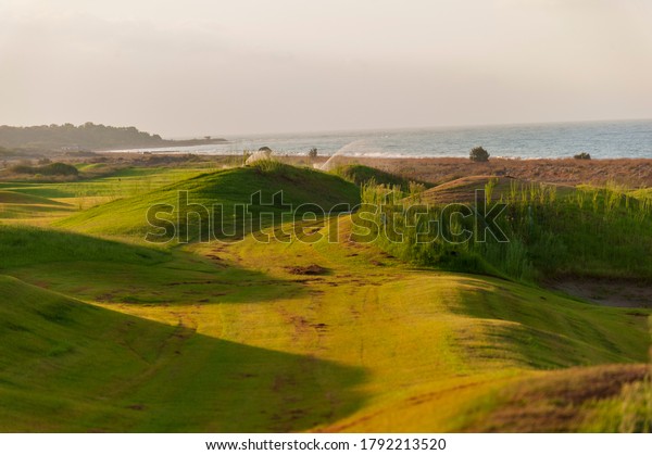 View of green rolling landscape and irrigation or\
sand traps on the golf\
course