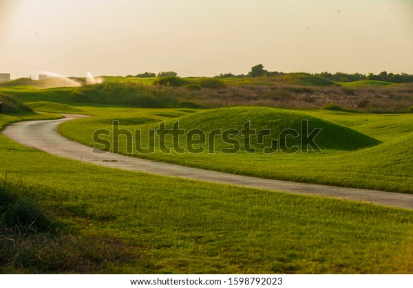 View of green rolling landscape and watering or\
sand traps on golf course