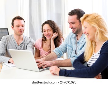View of a Group of 4 young attractive people working on a laptop