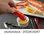 A view of a hand dipping some king crab leg meat into a condiment cup of butter.