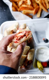 A View Of A Hand Holding A Slice Of A Chicken Shawarma Wrap.