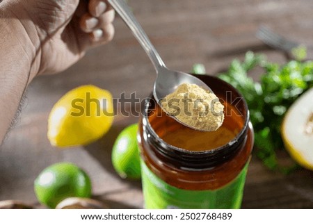 A view of a hand holding a spoon full of chicken bouillon powder.