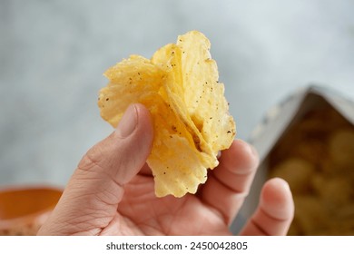 A view of a hand holding a stack of ridged potato chips. - Powered by Shutterstock