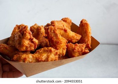 A View Of A Hand Holding A Tray Of Breaded Deep Fried Chicken Wings.