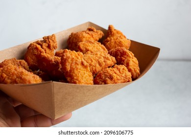 A View Of A Hand Holding A Tray Of Chicken Strips.