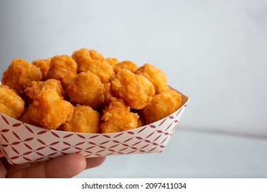 A View Of A Hand Holding A Tray Of Chicken Nuggets.