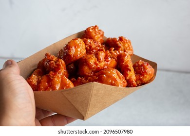 A View Of A Hand Holding A Tray Of Glazed Boneless Chicken Wings.