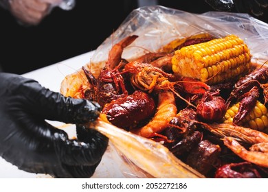 A View Of Hand Opening A Plastic Bag Full Of Seafood Boil, At A Local Restaurant.