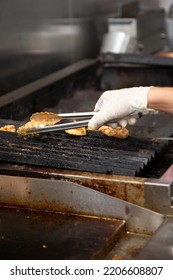 A View Of A Hand Preparing Grilled Chicken On A Restaurant Grade Stove.